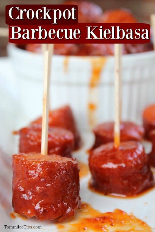 Crockpot Barbecue Kielbasa text over a white platter with kielbasa bites with toothpicks and a bowl of kielbasa in the backgroun. 