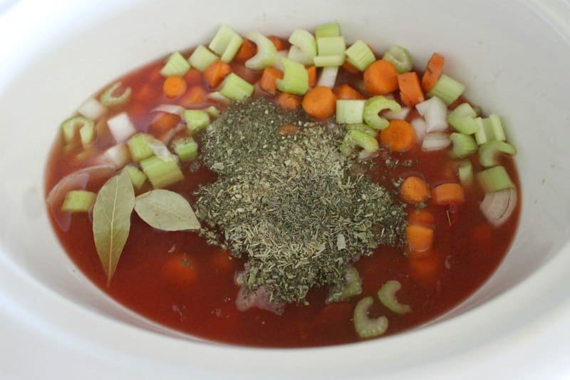 vegetables and spices in a white slow cooker bowl 