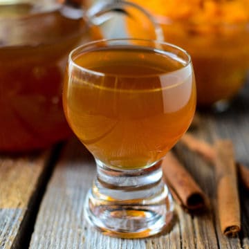 Pumpkin Liqueur in a glass next to cinnamon sticks