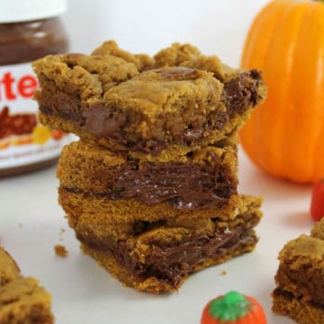 Pumpkin Nutella Bars stacked next to a jar of Nutella in the background and a pumpkin