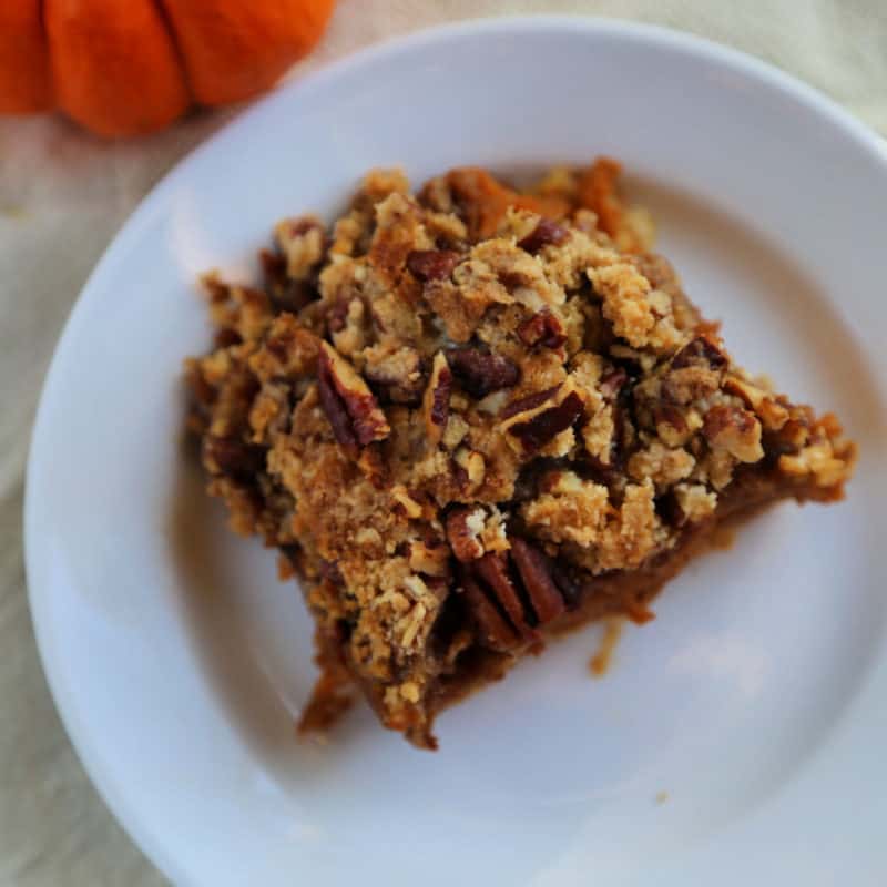 Pumpkin Pie Bar square on a white plate near a pumpkin