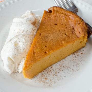 Pumpkin Pie Pudding Cake on a white plate with a garnish of whipped cream