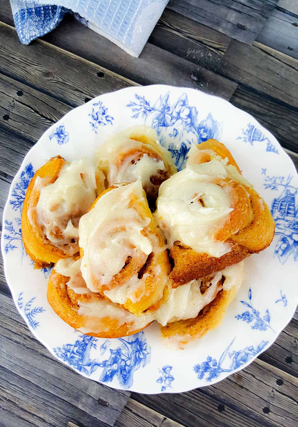 iced cinnamon rolls on a blue and white plate