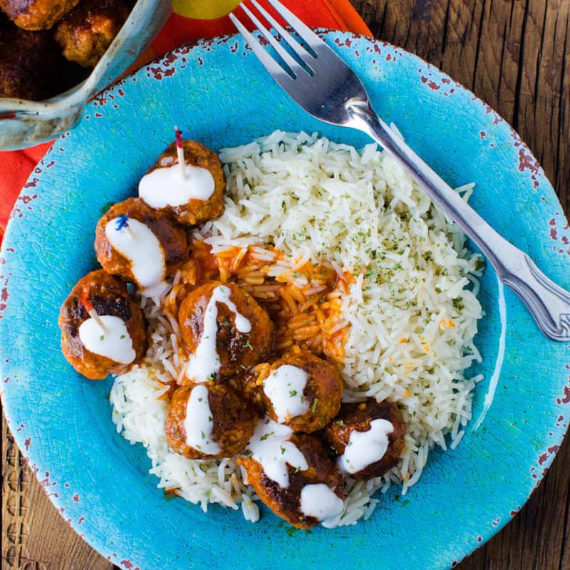 Buffalo Chicken meatballs next to white rice on a blue plate with a fork