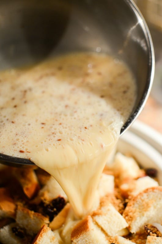 eggnog batter pouring over bread in a slow cooker bowl 