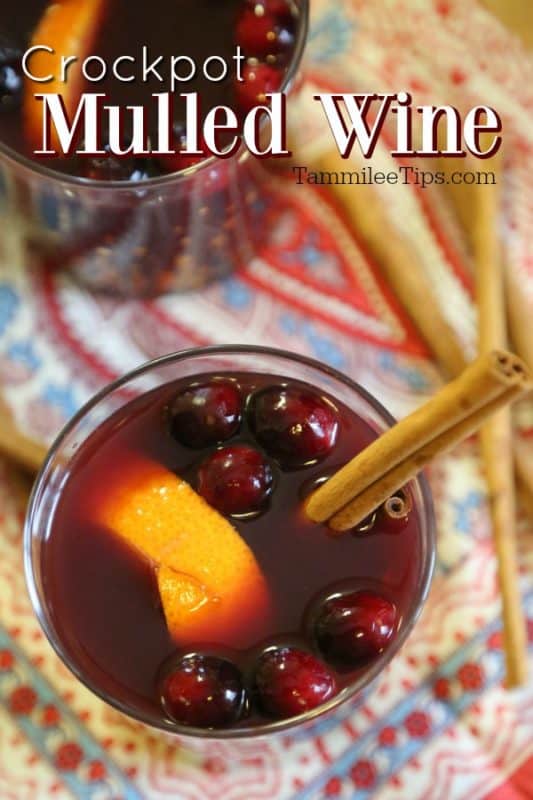 Crockpot mulled wine over two glasses with red wine, cranberries, orange peel, and cinnamon sticks. 