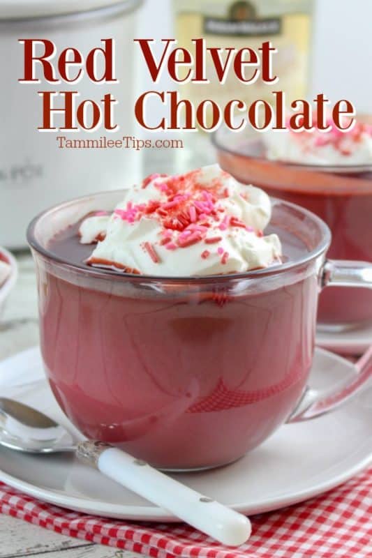 Red Velvet Hot Chocolate text over a glass coffee mug with red velvet hot chocolate with whipped cream and pink sprinkles