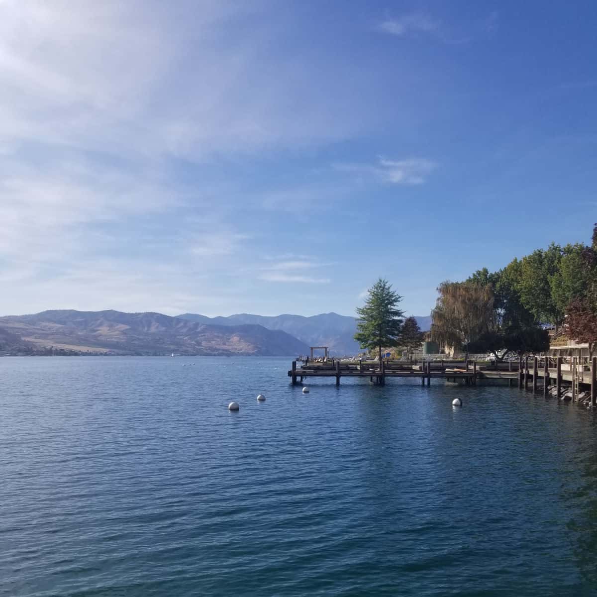 Looking down the lake with a dock on the side and mountains in the backgroun