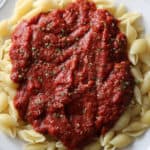 a white plate with marinara sauce on pasta shells