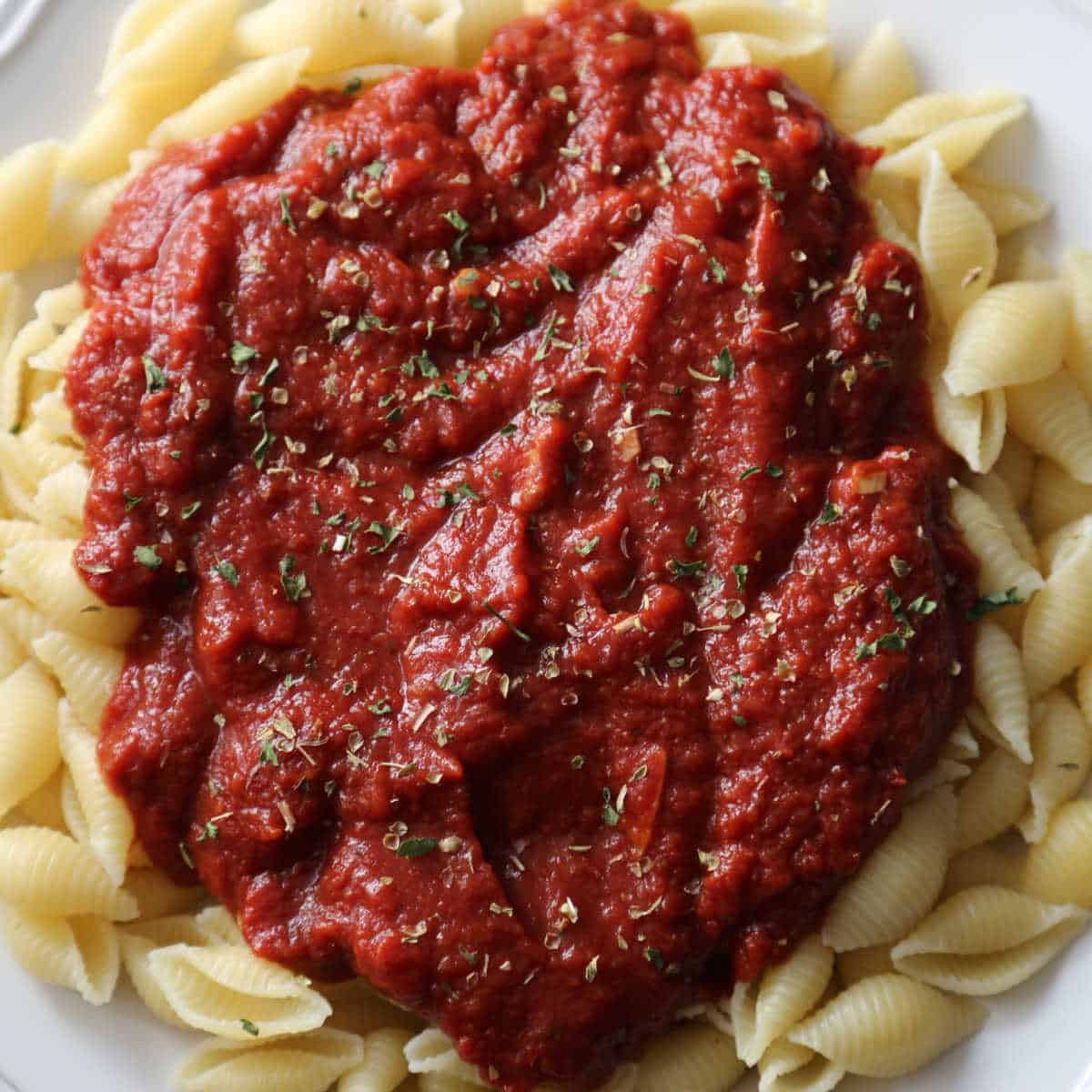 a white plate with marinara sauce on pasta shells