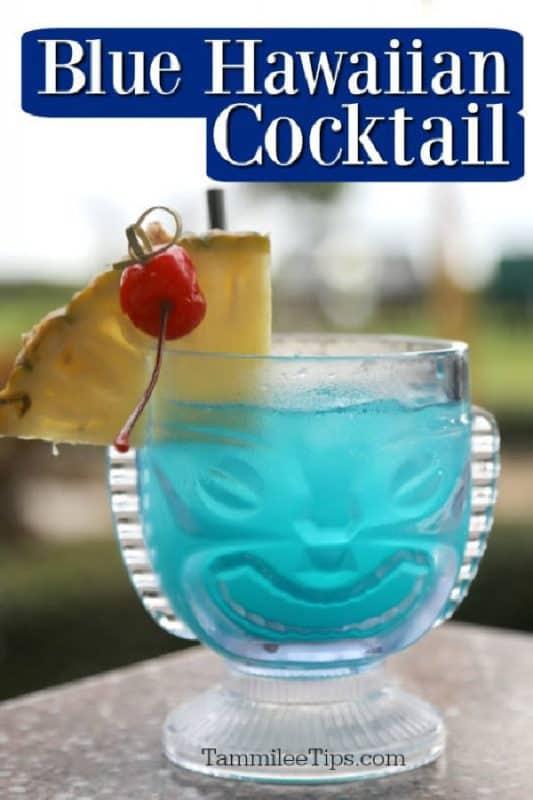 Blue Hawaiian Cocktail over a tiki glass with a blue drink, pineapple cherry garnish