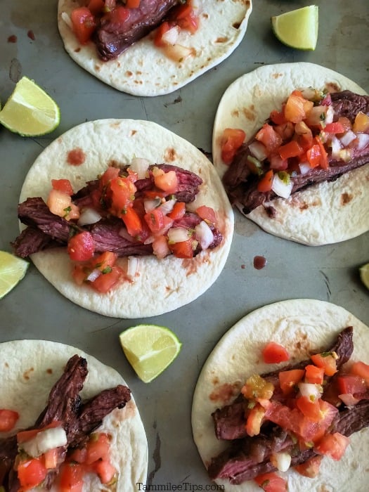 Carne Asada Street Tacos on a baking sheet with lime wedges