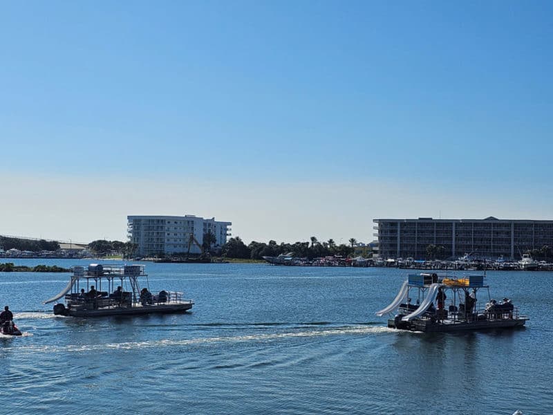 Two Pontoon boats with slide off of them on the water