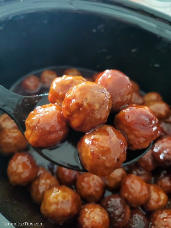 Grape Jelly Meatballs on a spoon above a black crockpot 