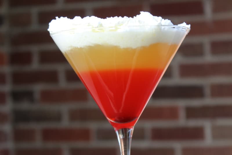 Candy Corn Cocktail in a martini glass with a brick background