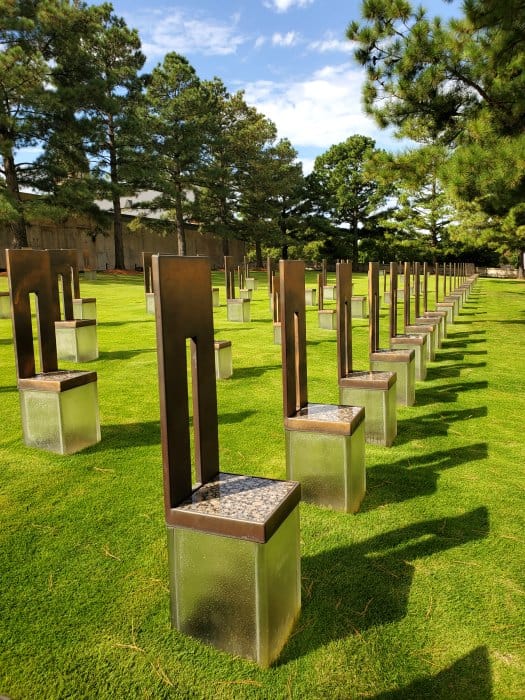 Memorial chairs lined on a green lawn with trees