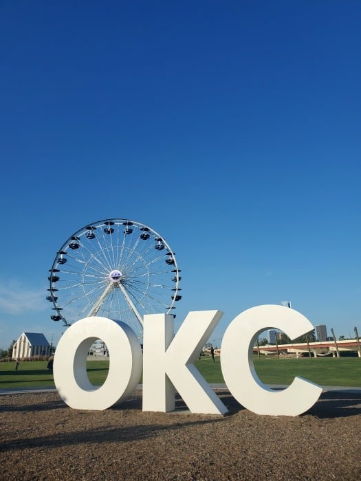 Ferris wheel behind a OKC white sign