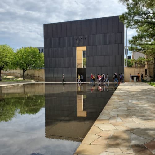 Oklahoma City Memorial reflecting in pool with ranger led group of people