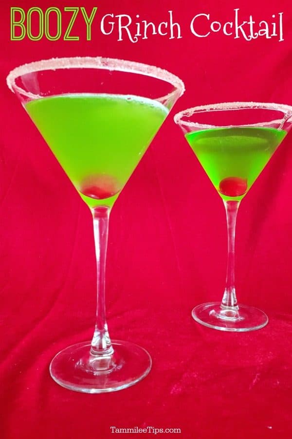 two boozy grinch cocktails in martini glasses with a maraschino cherry