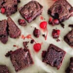 Bourbon Cherry Brownies cut into squares on parchment paper with maraschino cherries