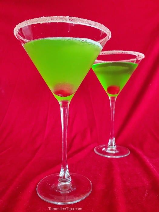 green martini with a maraschino cherry sitting on a red background
