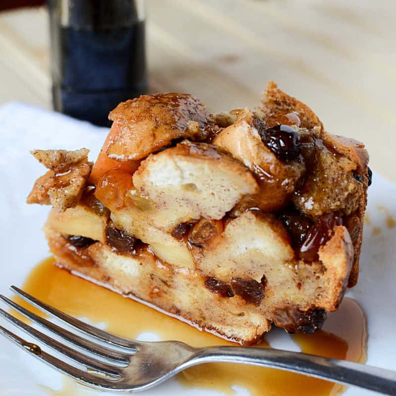 Apple Raisin French Toast on a white plate with syrup and a silver spoon