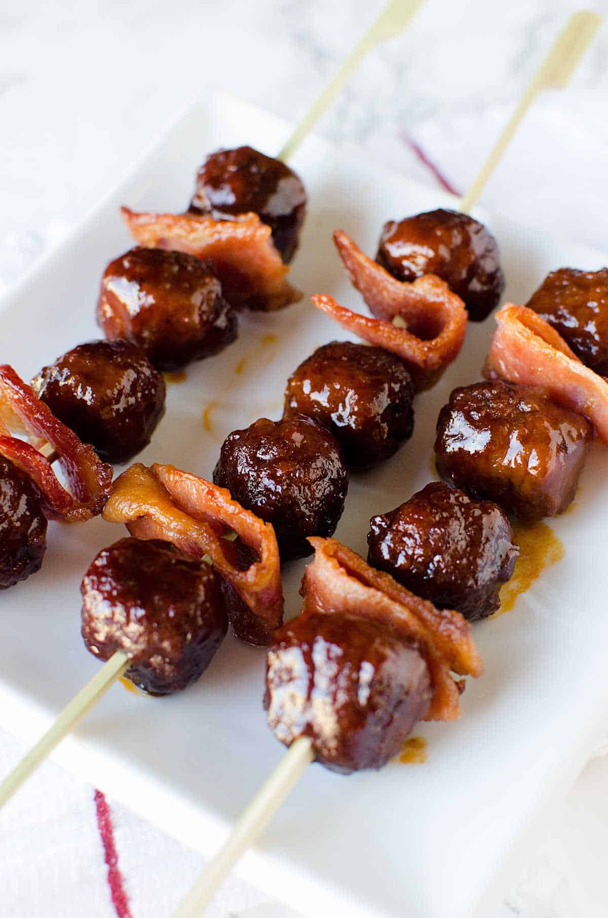 Bacon and bourbon meatballs on wooden skewers in a white plate