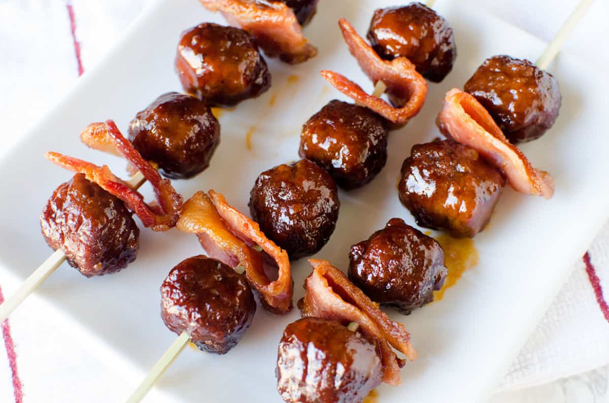 bacon and bourbon meatballs on skewers on a white platter