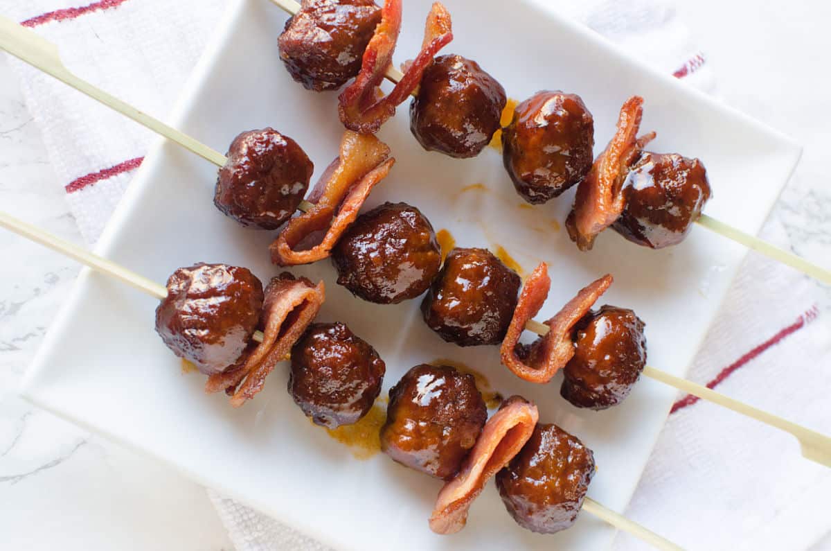 Bacon and meatballs on a skewer sitting on a white plate
