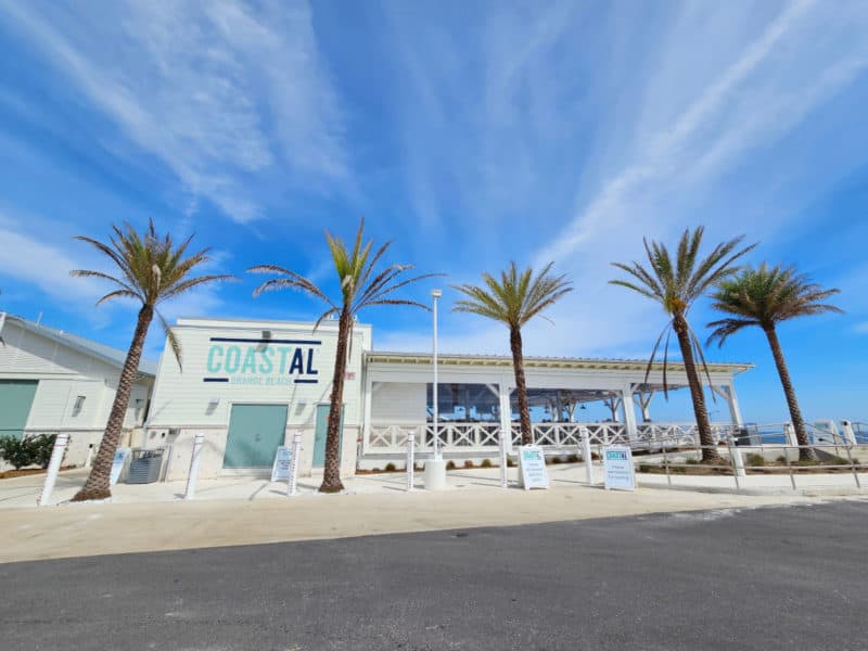 CoastAL Restaurant exterior with palm trees and blue skies