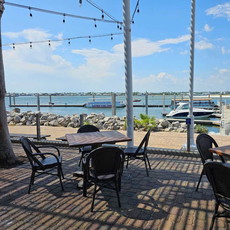 outdoor tables and chairs with a view of the water and boats at Cobalt