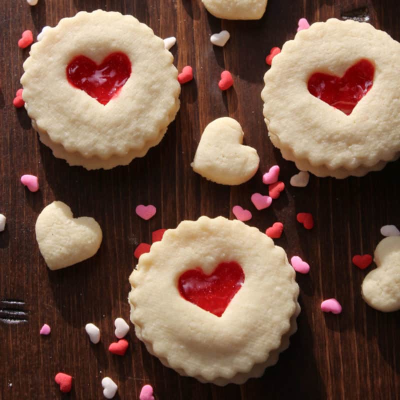 Red Heart Valentine's Day Cookies on a wood board with heart sprinkles