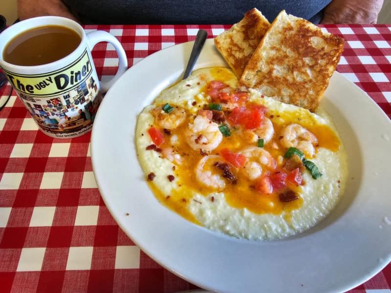 Shrimp and Grits next to an ugly diner mug on a checkered table cloth