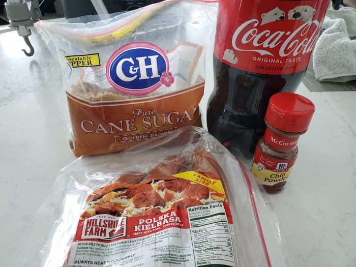 Brown sugar, kielbasa, chili powder, and coca cola on a white counter