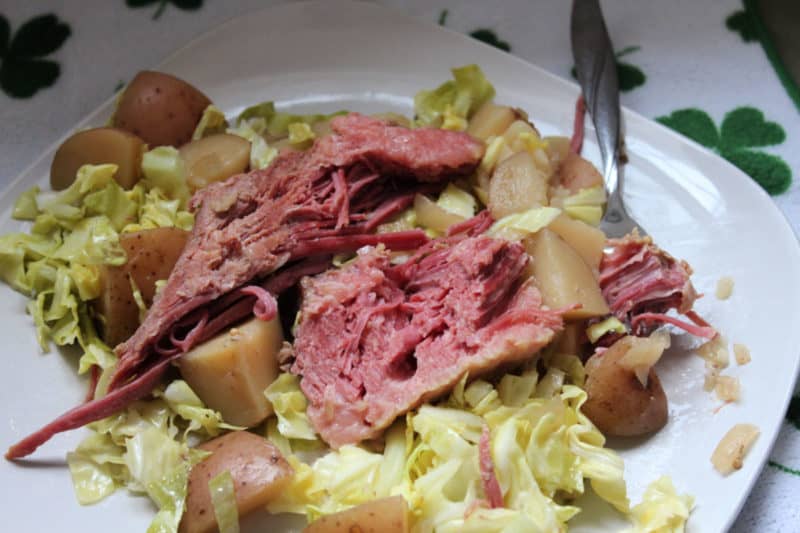 Corned Beef Cabbage and Potatoes on a white plate with a fork. 