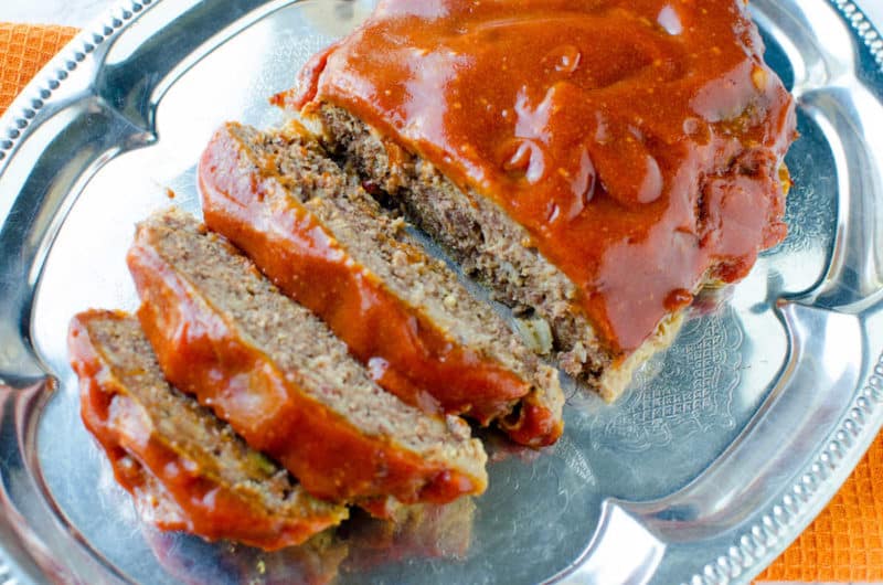 crock pot meatloaf sliced on a silver platter with meatloaf sauce