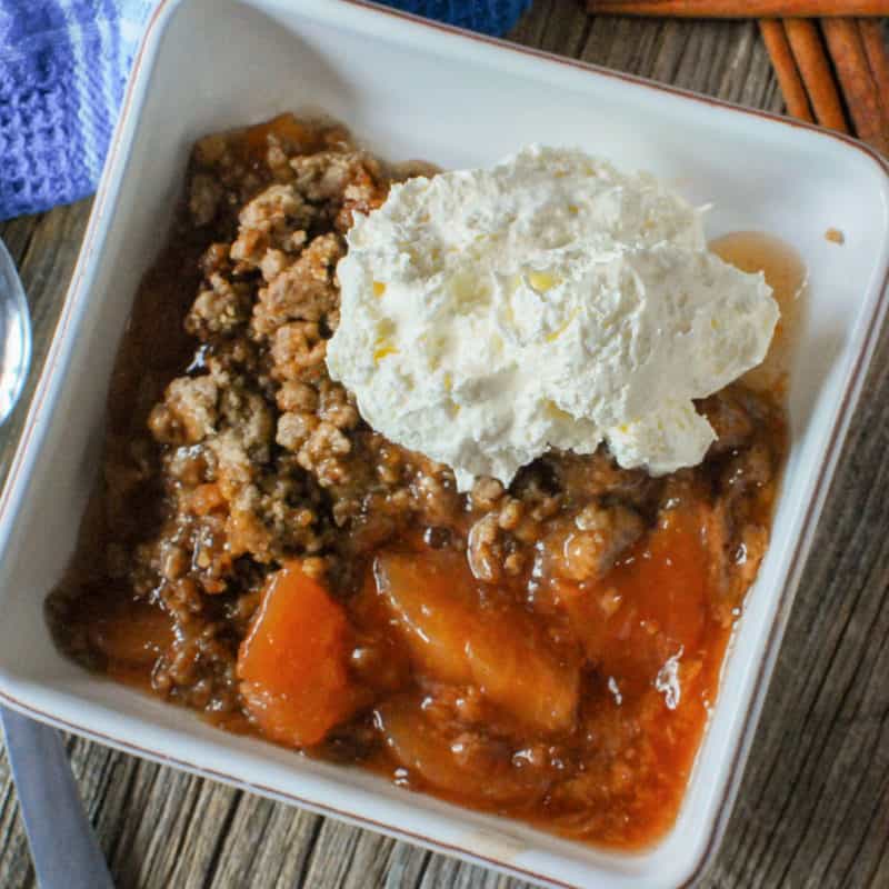 Apple spice dump cake in a white bowl with whipped cream