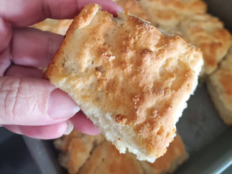 7 Up biscuit being held above a pan of biscuits