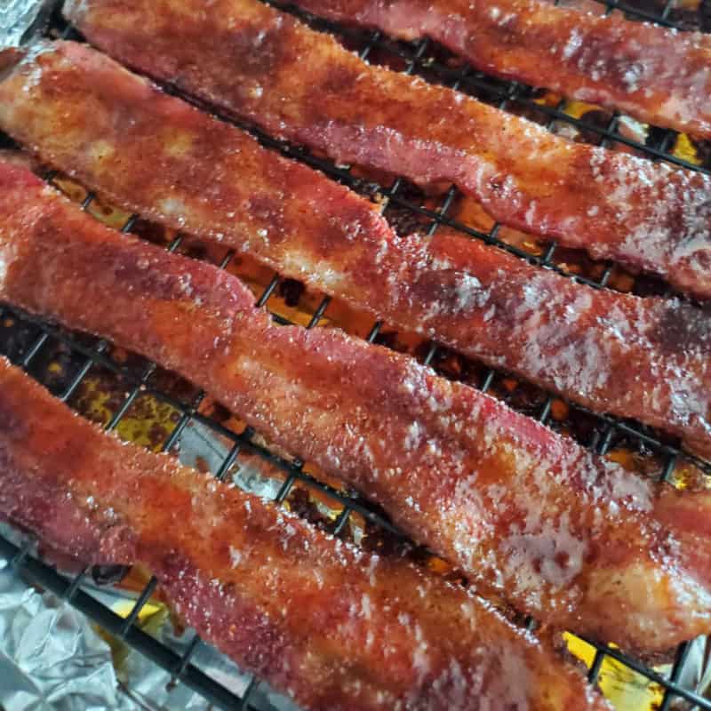 Strips of bacon candy on a wire rack over aluminum foil