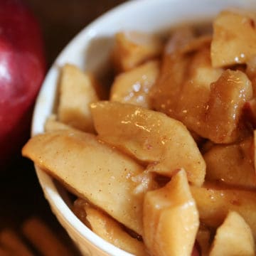 Crock Pot Fried Apples in a white bowl next to a red apple