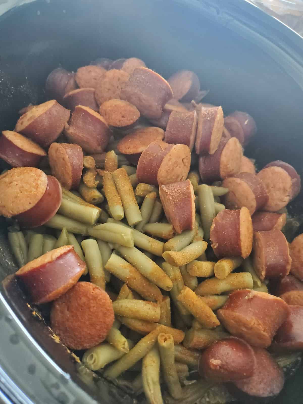 kielbasa pieces with green beans in a slow cooker