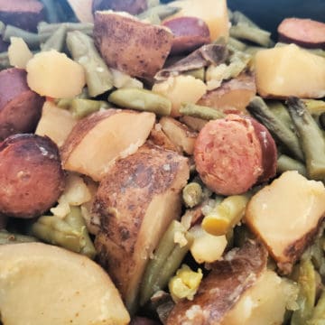 Crockpot Kielbasa potatoes and green beans in a dark slow cooker bowl