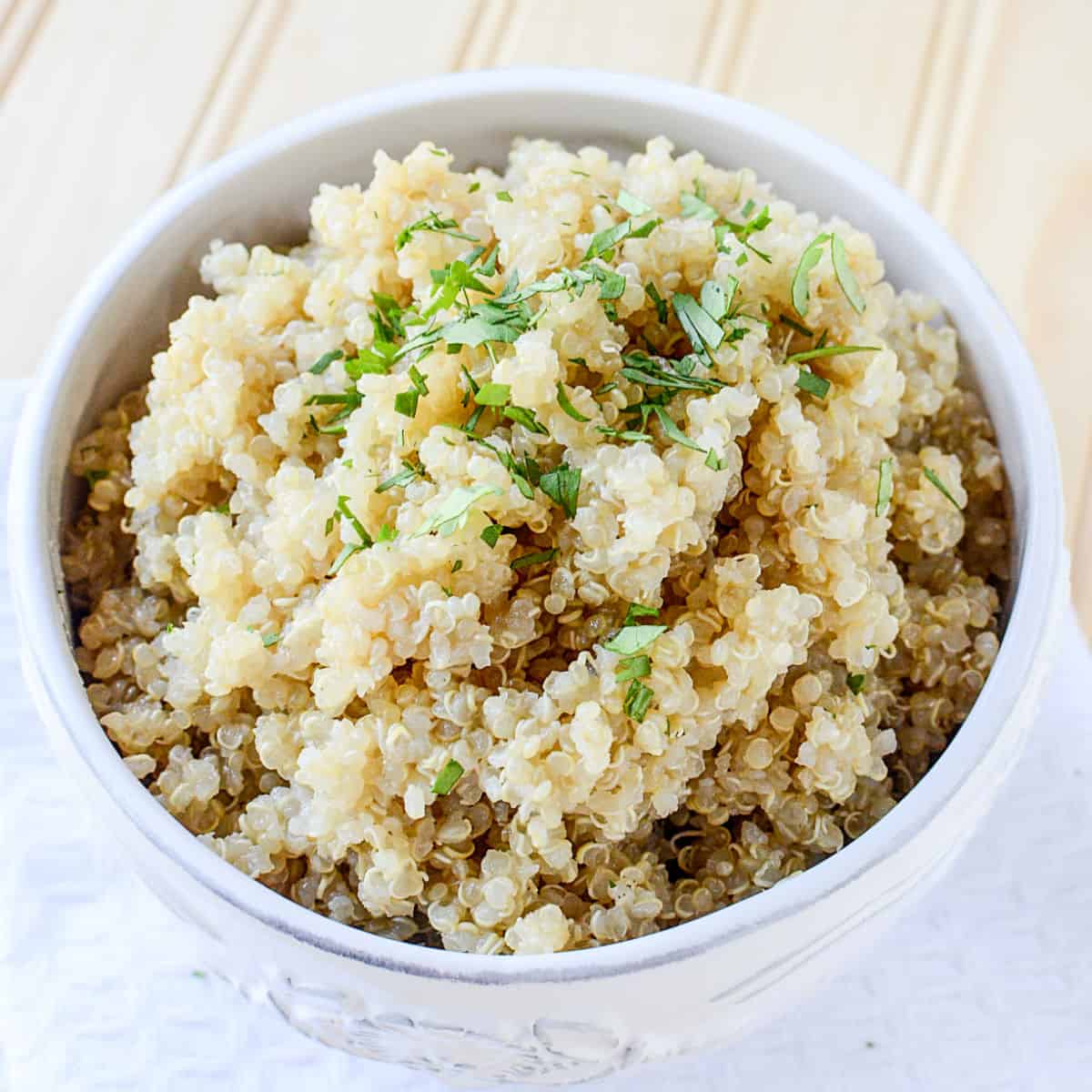 Cooked Quinoa in a white bowl on a white napkin