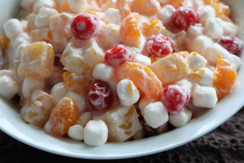 Marshmallow fruit salad in a white bowl on a black background