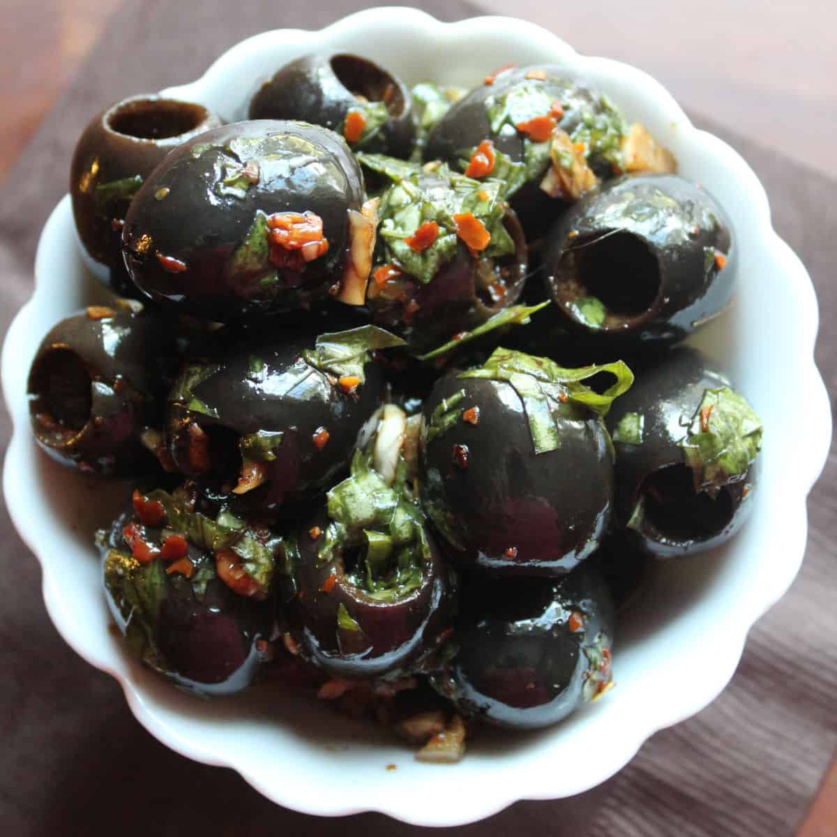 marinated olives in a white bowl on a brown napkin