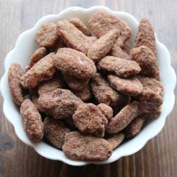 Candied Pecans in a white bowl on a wood board