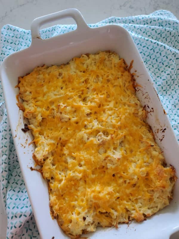 Cracker Barrel Hash Brown Casserole in a white square baking dish on a cloth napkin