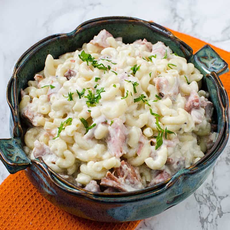 Macaroni and Cheese with ham in a clay bowl on a orange napkin