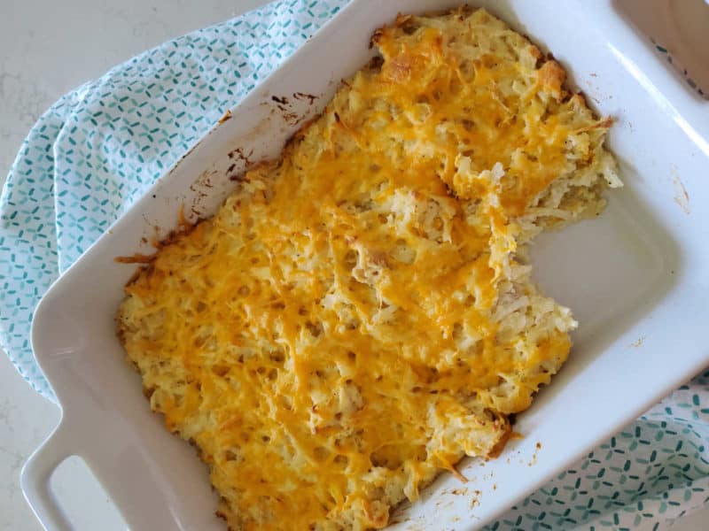 Cracker Barrel Hashbrown Casserole in a white square baking dish on a cloth napkin 