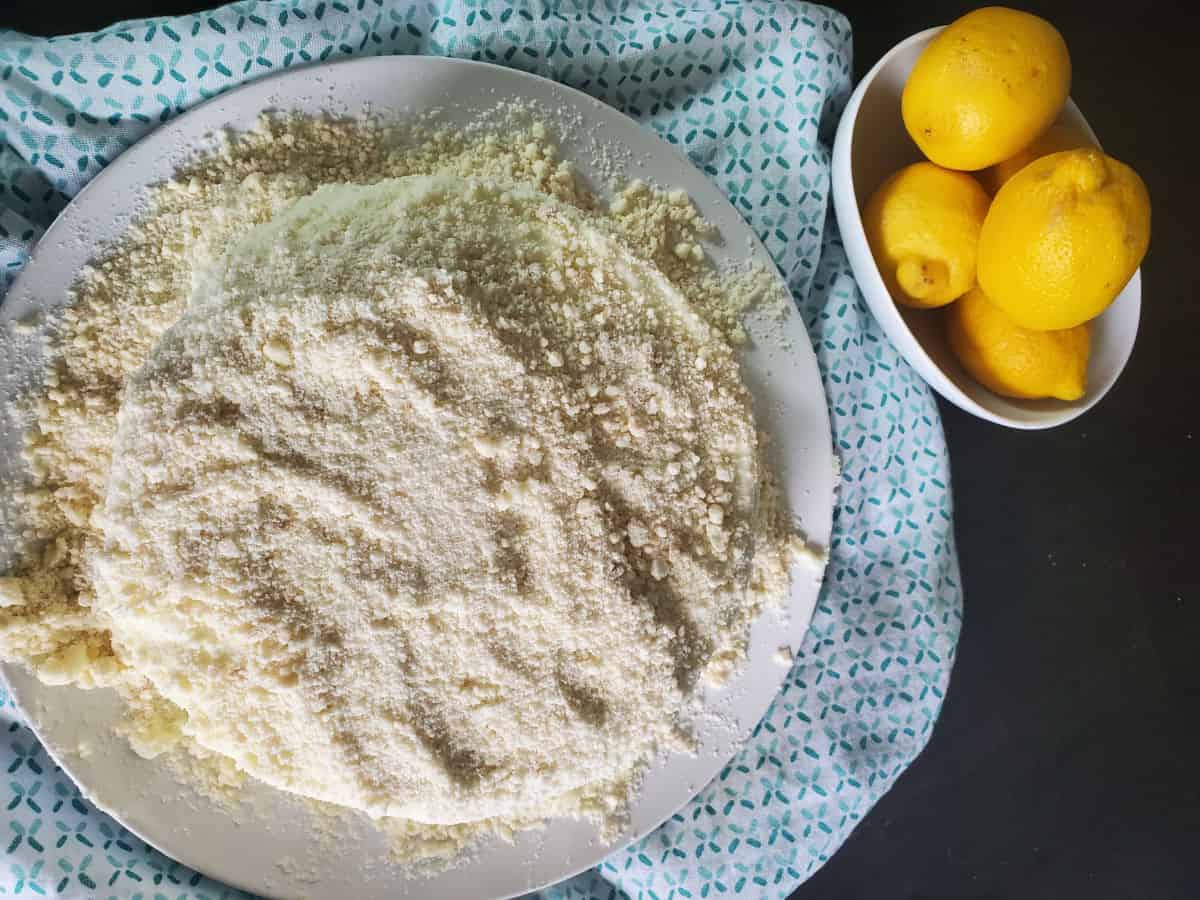 Looking down on a lemon cream cake next to a bowl of lemons